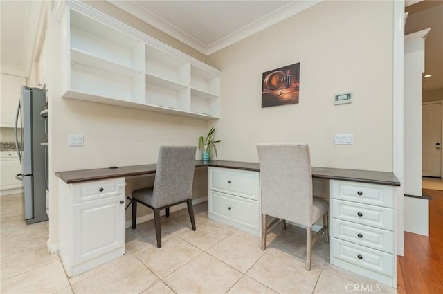 home office with light tile patterned floors, ornamental molding, built in study area, and baseboards