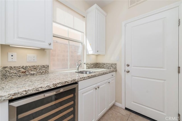 kitchen with light stone counters, wine cooler, visible vents, white cabinetry, and a sink