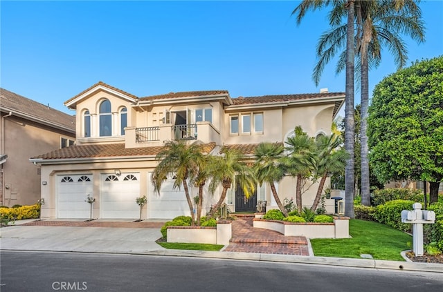 mediterranean / spanish-style home featuring concrete driveway, a tile roof, a balcony, and stucco siding