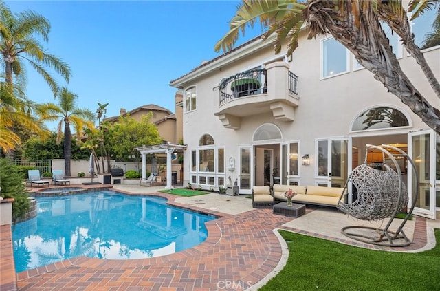 rear view of house with a patio, a balcony, fence, stucco siding, and a pergola