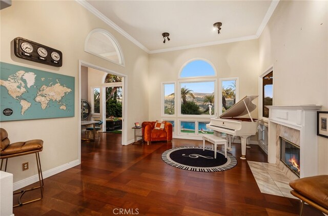 sitting room featuring baseboards, ornamental molding, wood finished floors, and a high end fireplace