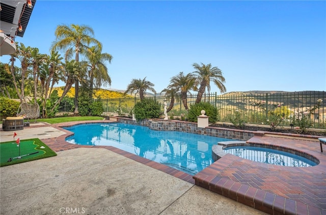 view of swimming pool with a pool with connected hot tub, a fenced backyard, and a patio