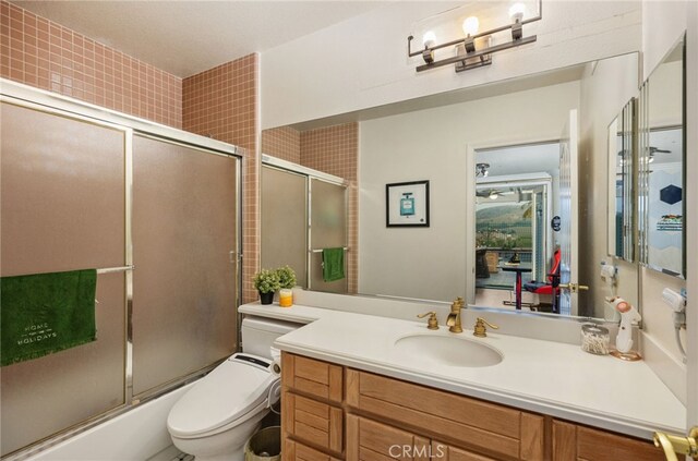 bathroom with toilet, enclosed tub / shower combo, and vanity