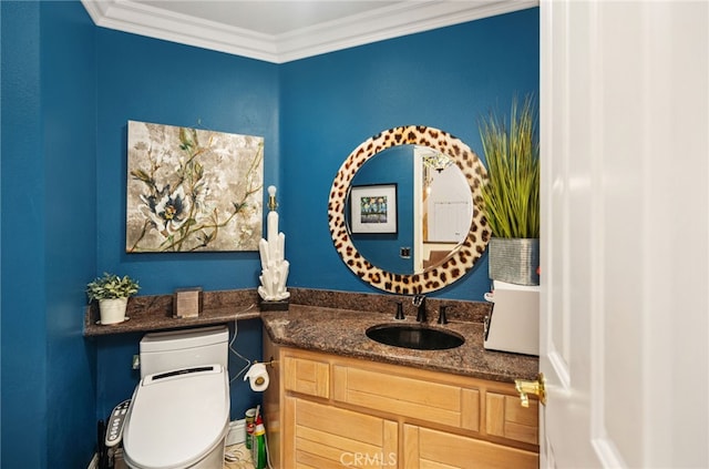 bathroom with toilet, vanity, and crown molding