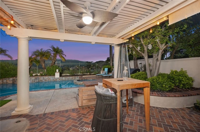 patio terrace at dusk with a pool with connected hot tub, a fenced backyard, a ceiling fan, and a pergola