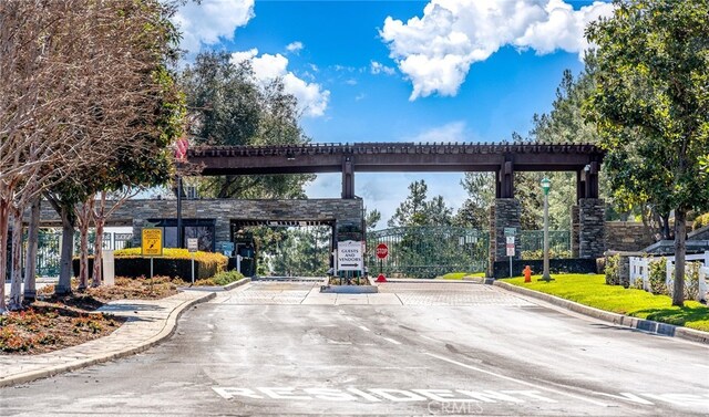 view of road featuring curbs, a gated entry, and traffic signs