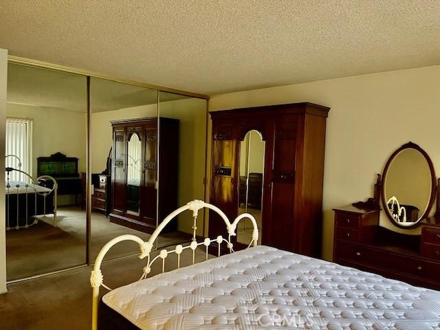 bedroom featuring carpet floors, arched walkways, a closet, and a textured ceiling