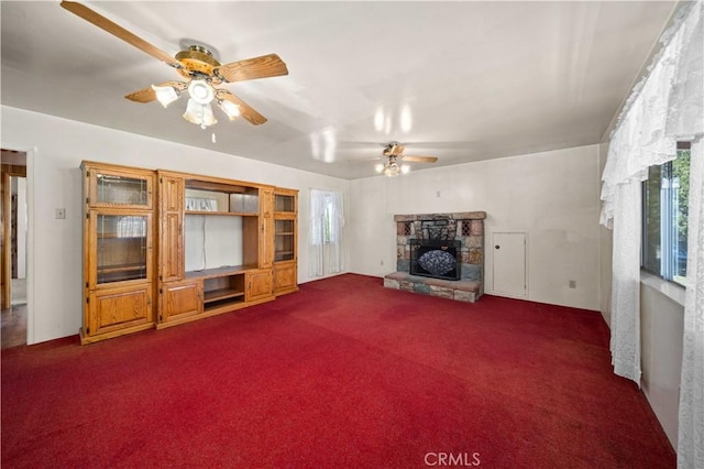 unfurnished living room featuring a fireplace, dark colored carpet, and a ceiling fan