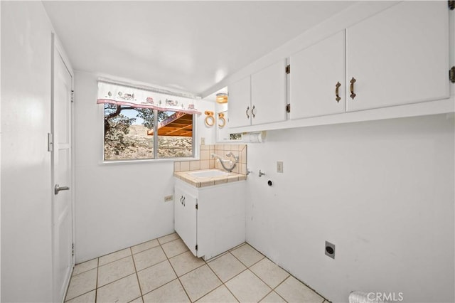 clothes washing area with a sink, cabinet space, light tile patterned floors, and electric dryer hookup