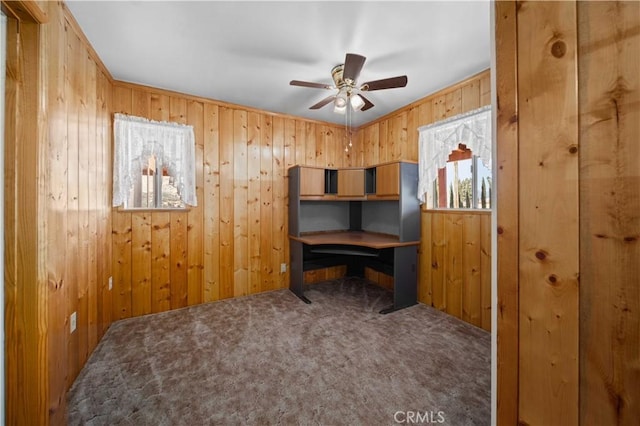 office space with carpet floors, wooden walls, and a ceiling fan