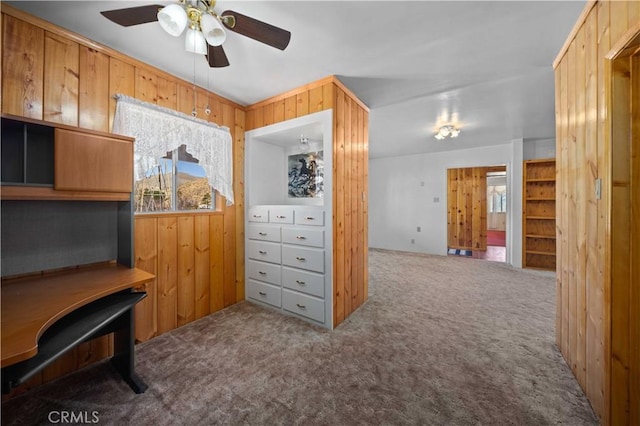 carpeted office featuring wood walls and ceiling fan