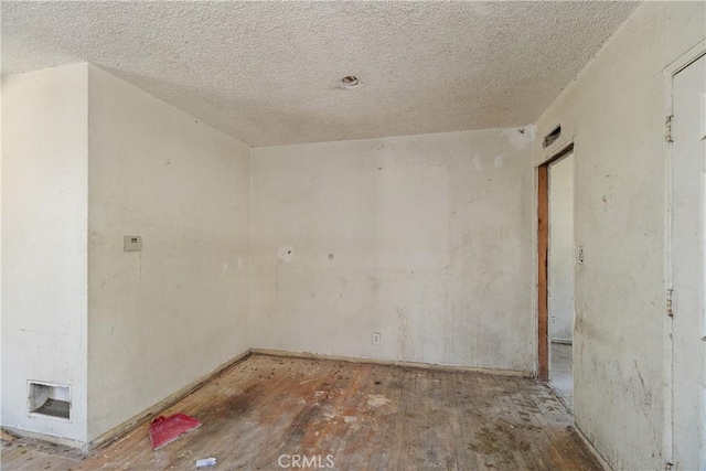 spare room featuring a textured ceiling and wood finished floors