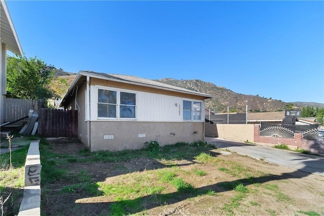 view of property exterior with crawl space, fence, and a mountain view