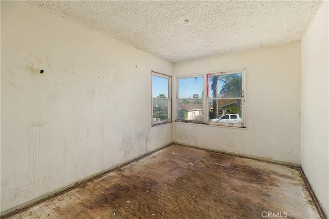 unfurnished room featuring hardwood / wood-style flooring and a textured ceiling