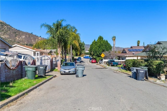 view of street featuring curbs, traffic signs, a gate, and a mountain view