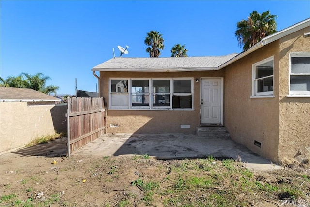 rear view of property with crawl space, a patio area, fence, and stucco siding