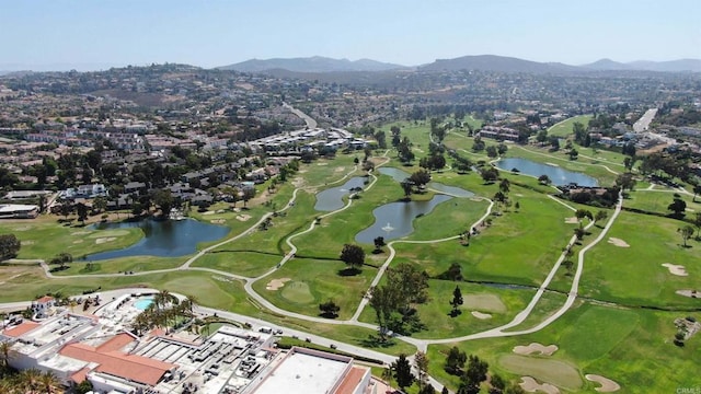 drone / aerial view with view of golf course and a water and mountain view