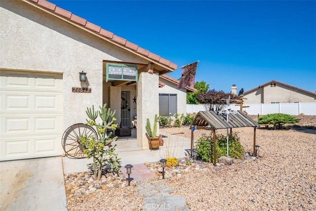 exterior space with a garage, fence, and stucco siding