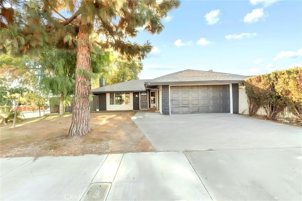 ranch-style house with concrete driveway, brick siding, and an attached garage