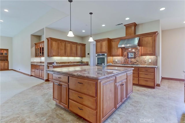 kitchen with stone countertops, visible vents, wall chimney exhaust hood, stovetop, and a sink