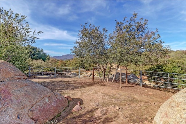 view of yard featuring a rural view, fence, and a mountain view