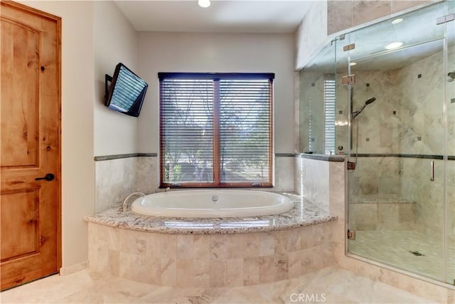 bathroom featuring a garden tub and a shower stall