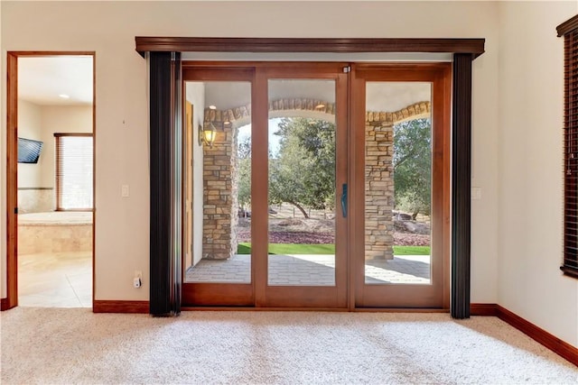 entryway featuring plenty of natural light, carpet, and baseboards