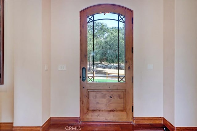 doorway with baseboards and wood finished floors