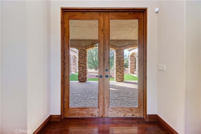 doorway featuring dark wood-type flooring, french doors, and baseboards