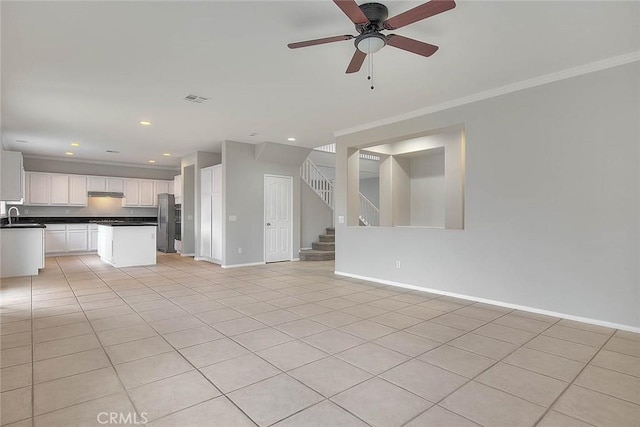 unfurnished living room with baseboards, visible vents, stairway, crown molding, and a sink