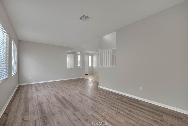 unfurnished room featuring baseboards, plenty of natural light, visible vents, and wood finished floors