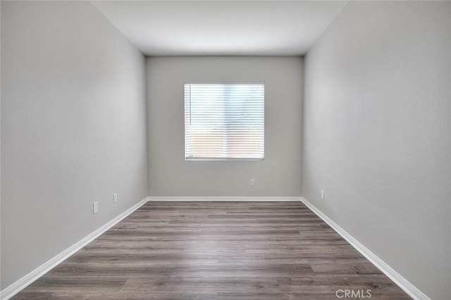 spare room with baseboards and wood finished floors