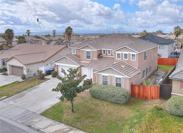 traditional-style house with driveway, a residential view, a tiled roof, fence, and stucco siding