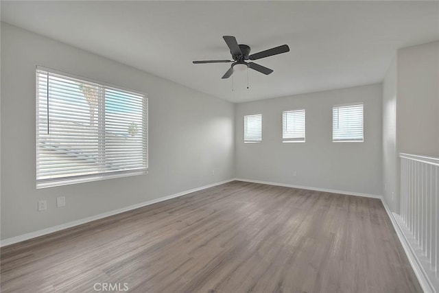 empty room with ceiling fan, baseboards, and wood finished floors