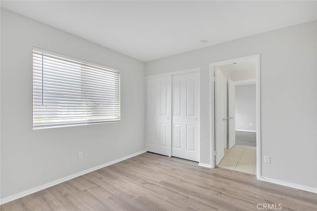 unfurnished bedroom with a closet, wood finished floors, and baseboards