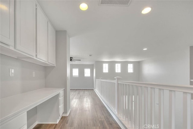 hallway with light wood-style floors, baseboards, visible vents, and recessed lighting