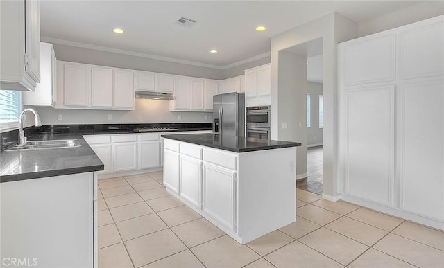 kitchen featuring appliances with stainless steel finishes, a sink, under cabinet range hood, and light tile patterned floors