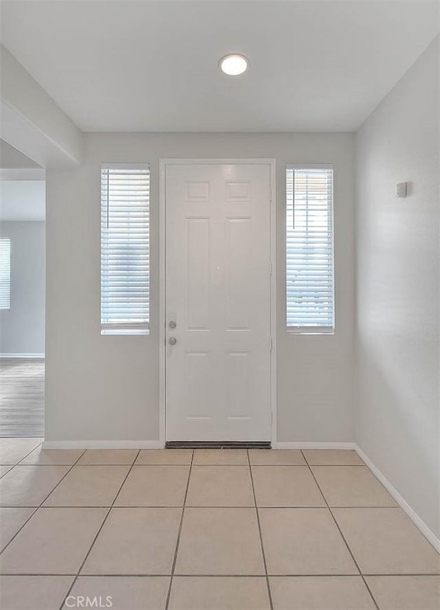 entryway with baseboards and light tile patterned flooring