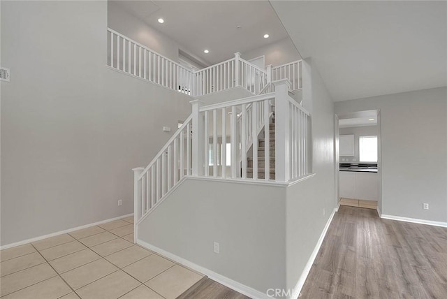 stairway featuring a high ceiling, recessed lighting, wood finished floors, and baseboards