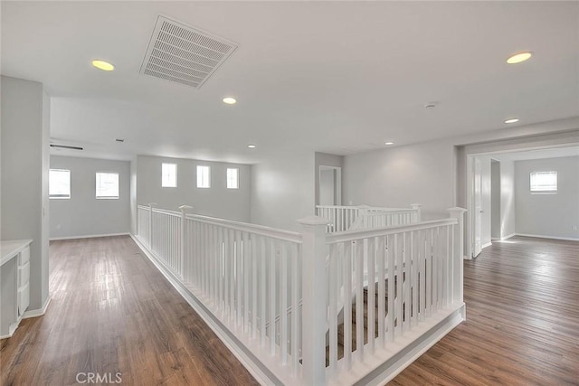 hallway with baseboards, wood finished floors, visible vents, and recessed lighting