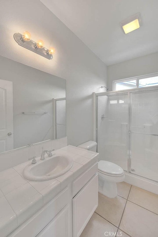 bathroom with toilet, a shower stall, vanity, and tile patterned floors