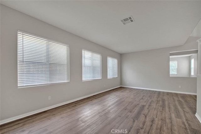 empty room featuring baseboards, visible vents, and wood finished floors