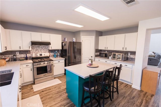 kitchen featuring stainless steel appliances, light countertops, visible vents, and under cabinet range hood