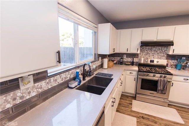 kitchen with under cabinet range hood, a sink, white cabinetry, light countertops, and stainless steel range with gas stovetop