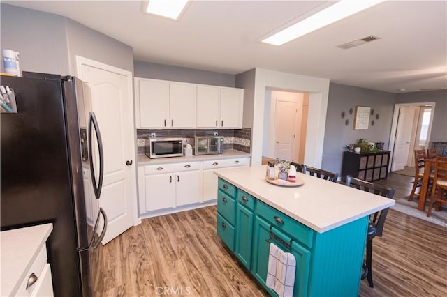 kitchen featuring stainless steel appliances, light countertops, visible vents, and white cabinets