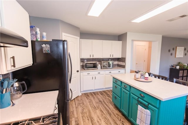 kitchen with light wood-style flooring, visible vents, white cabinetry, light countertops, and stainless steel microwave