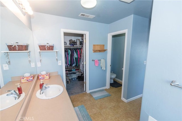 full bathroom with baseboards, visible vents, toilet, a spacious closet, and vanity