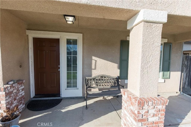 view of exterior entry featuring covered porch and stucco siding