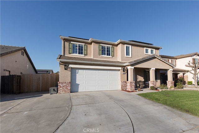 view of front facade with an attached garage, solar panels, fence, driveway, and stucco siding