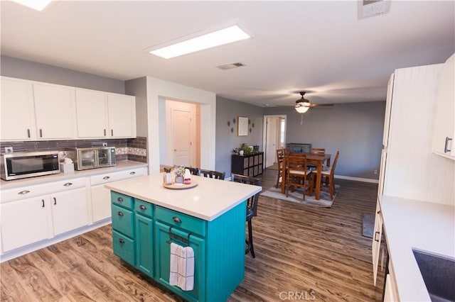 kitchen with visible vents, a kitchen breakfast bar, white cabinetry, light countertops, and stainless steel microwave